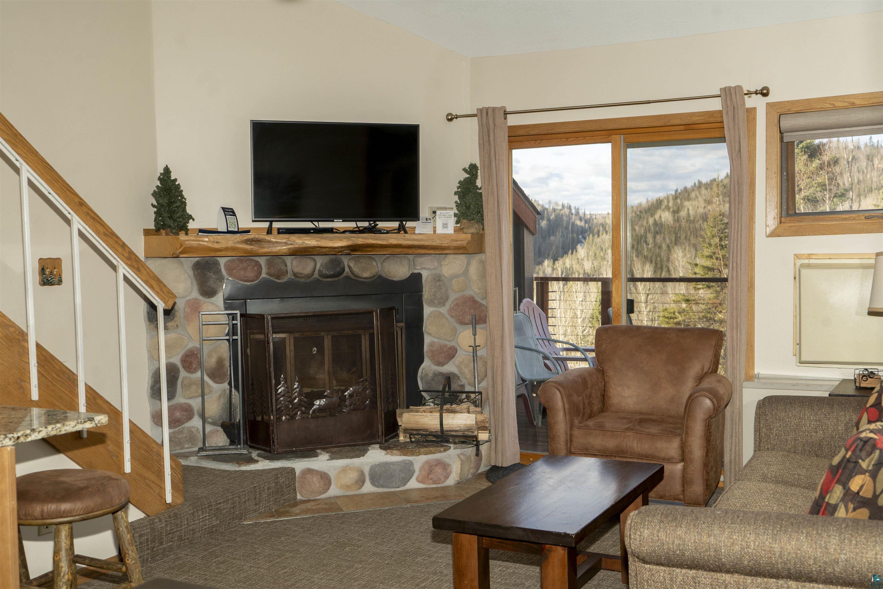 111 Bridge Run Lane, Unit 111 Lutsen, MN 55612 - Photo 26 of 48 Living area with a stone fireplace and stairway