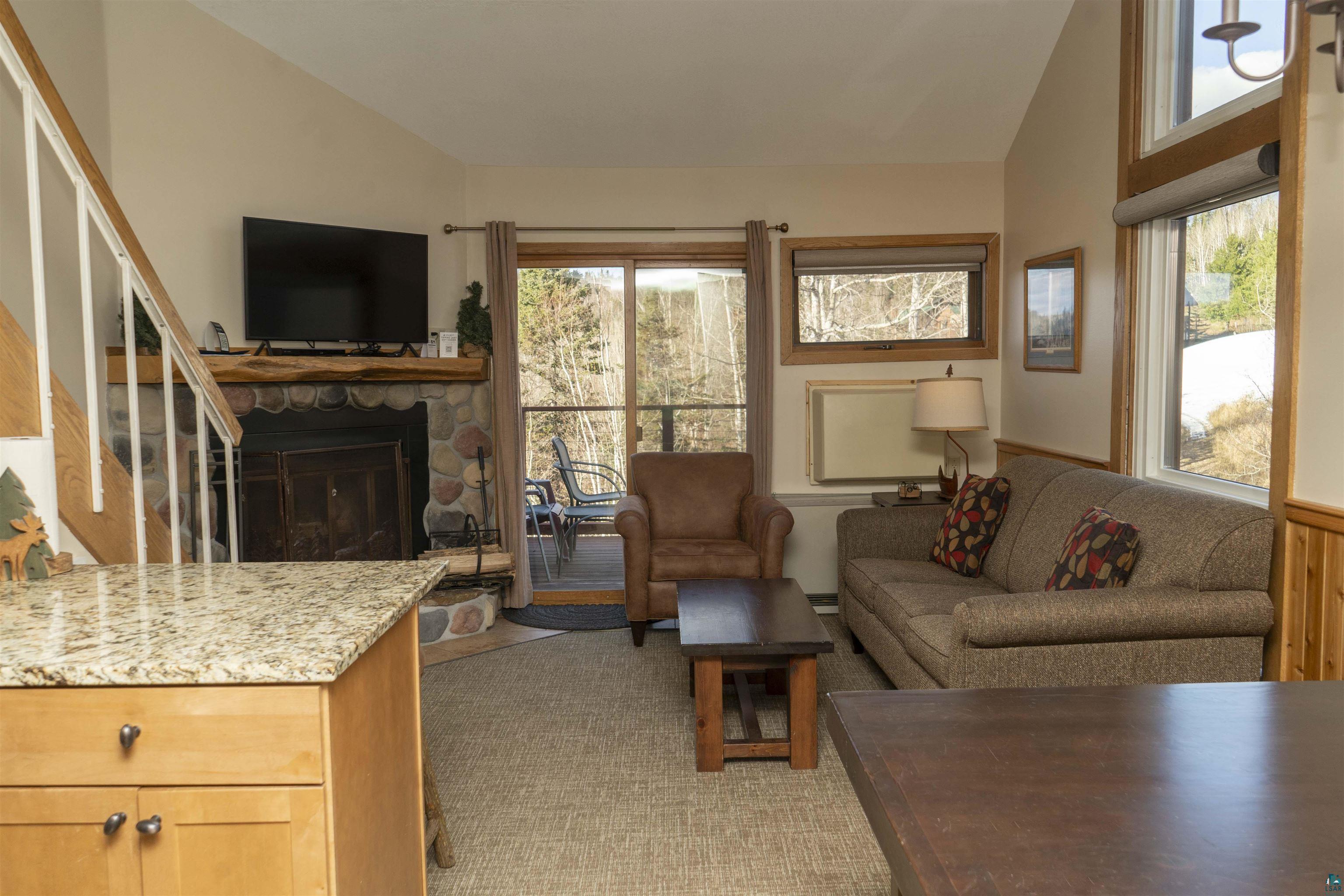 111 Bridge Run Lane, Unit 111 Lutsen, MN 55612 - Photo 28 of 48 Living area with a stone fireplace, vaulted ceiling, and stairway