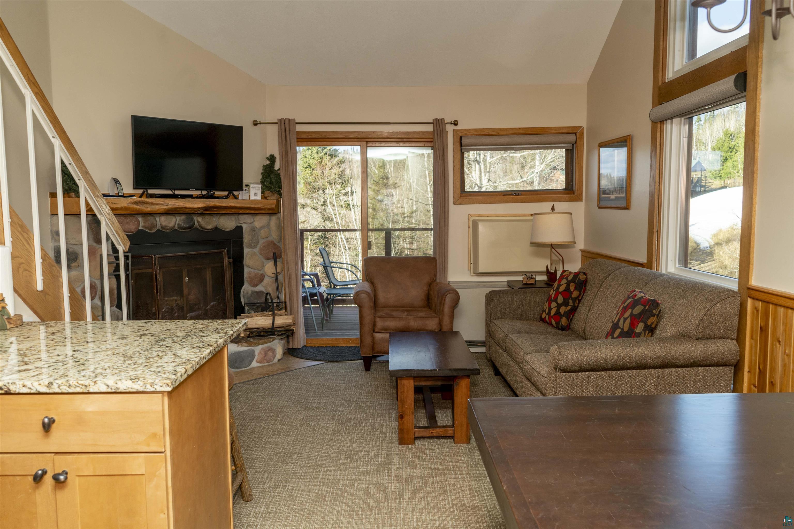 111 Bridge Run Lane, Unit 111 Lutsen, MN 55612 - Photo 29 of 48 Living area with vaulted ceiling, stairs, a fireplace, and plenty of natural light