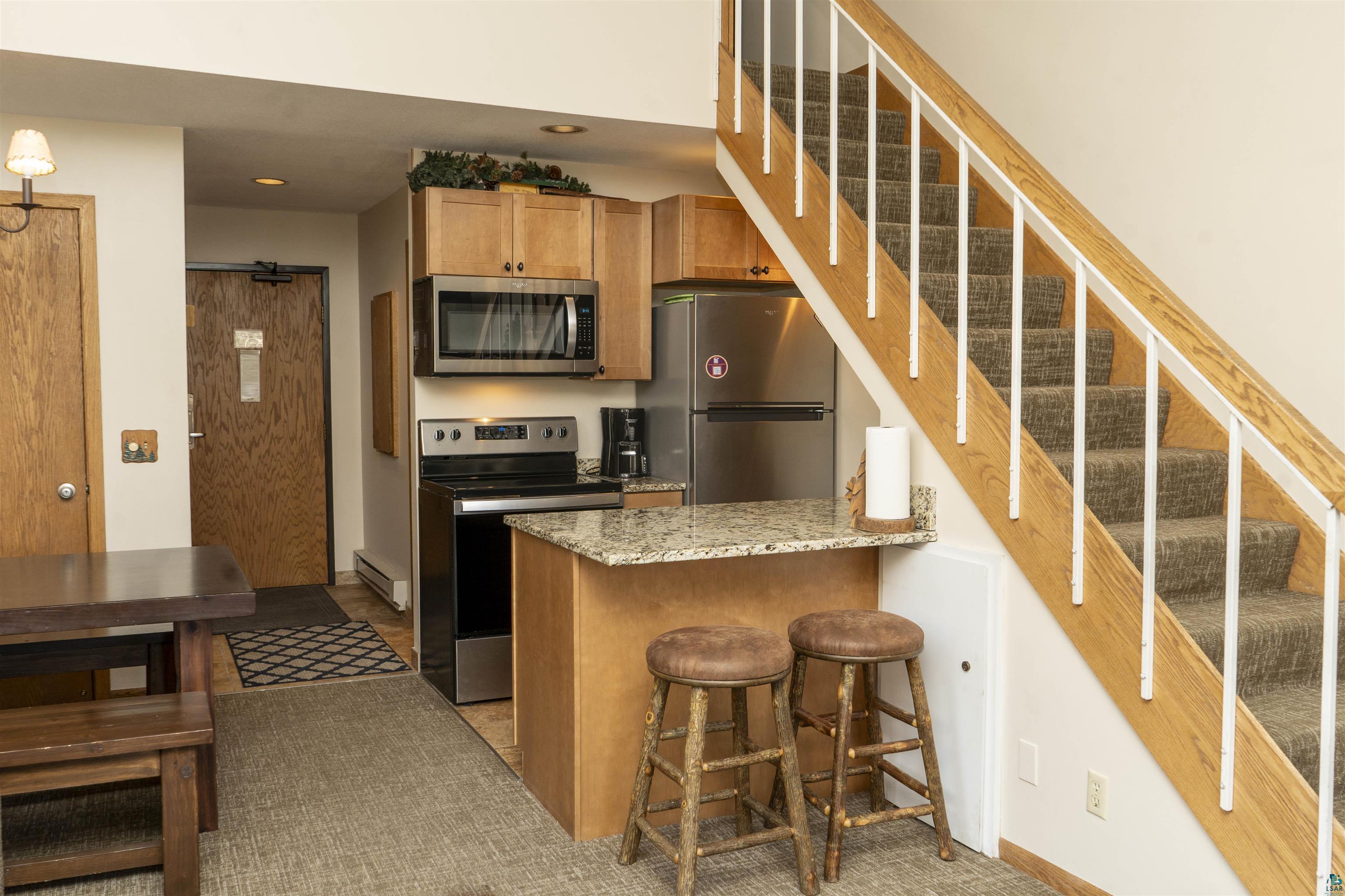 111 Bridge Run Lane, Unit 111 Lutsen, MN 55612 - Photo 5 of 48 Kitchen with stainless steel appliances, light stone countertops, a kitchen breakfast bar, a peninsula, and a baseboard radiator