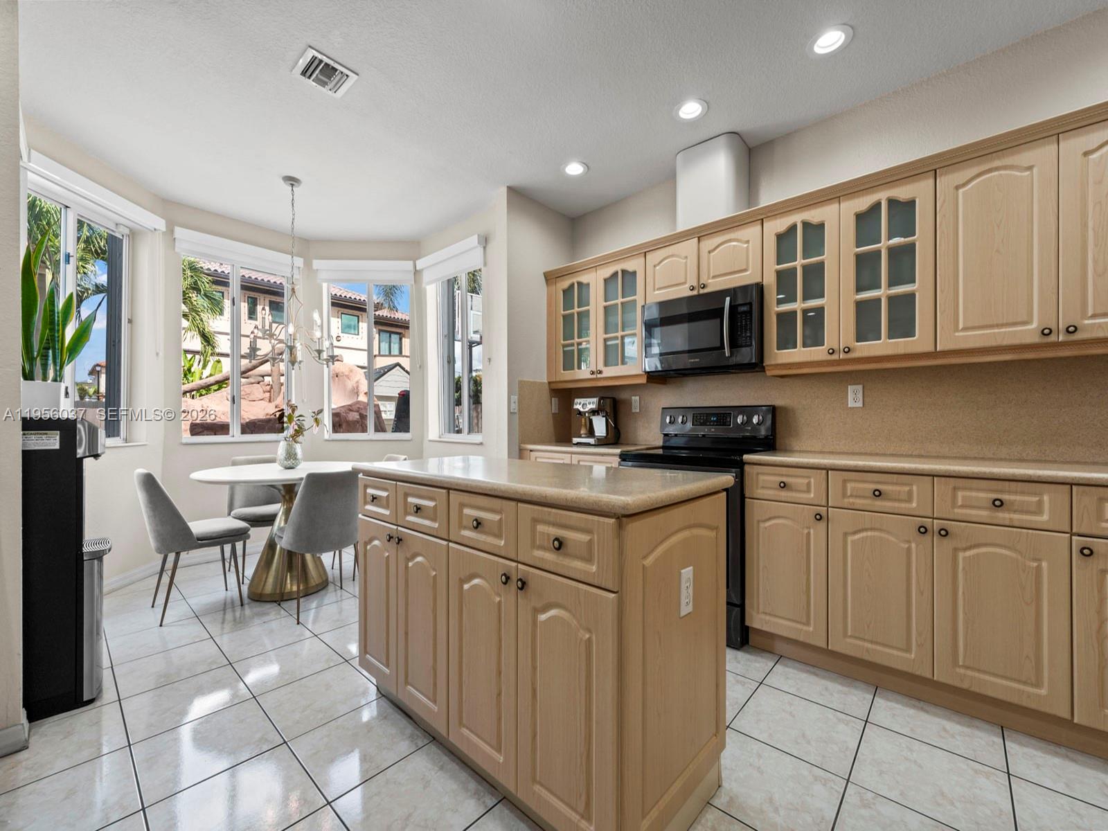 15383 Southwest 23rd Street Miami, FL 33185 - Photo 11 of 36 a kitchen with stainless steel appliances granite countertop a stove top oven a sink dishwasher a dining table and chairs with wooden floor