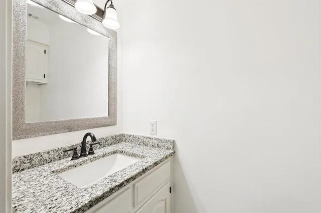 a bathroom with a granite countertop sink and a mirror