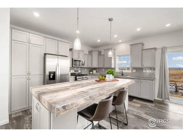 a kitchen with stainless steel appliances granite countertop a refrigerator a sink dishwasher a stove and white cabinets with wooden floor