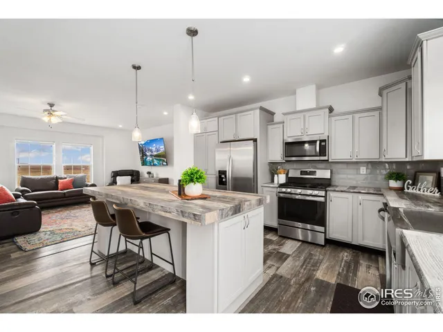 a kitchen with stainless steel appliances kitchen island granite countertop a table chairs and a refrigerator