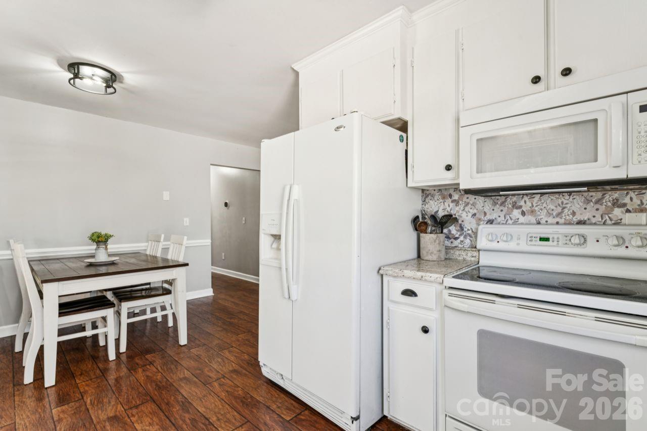 610 Eddleman Road Kannapolis, NC 28083 - Photo 15 of 34 a kitchen with a stove a refrigerator and a dining table with wooden floor