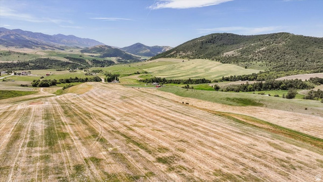 5588 East Glendale Road Preston, ID 83263 - Photo 6 of 11 Expansive land parcel featuring a harvested field foreground, rolling green hills, distant mountains, and scattered trees