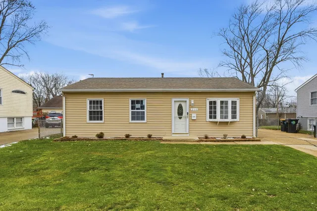 a front view of house with yard and trees in the background
