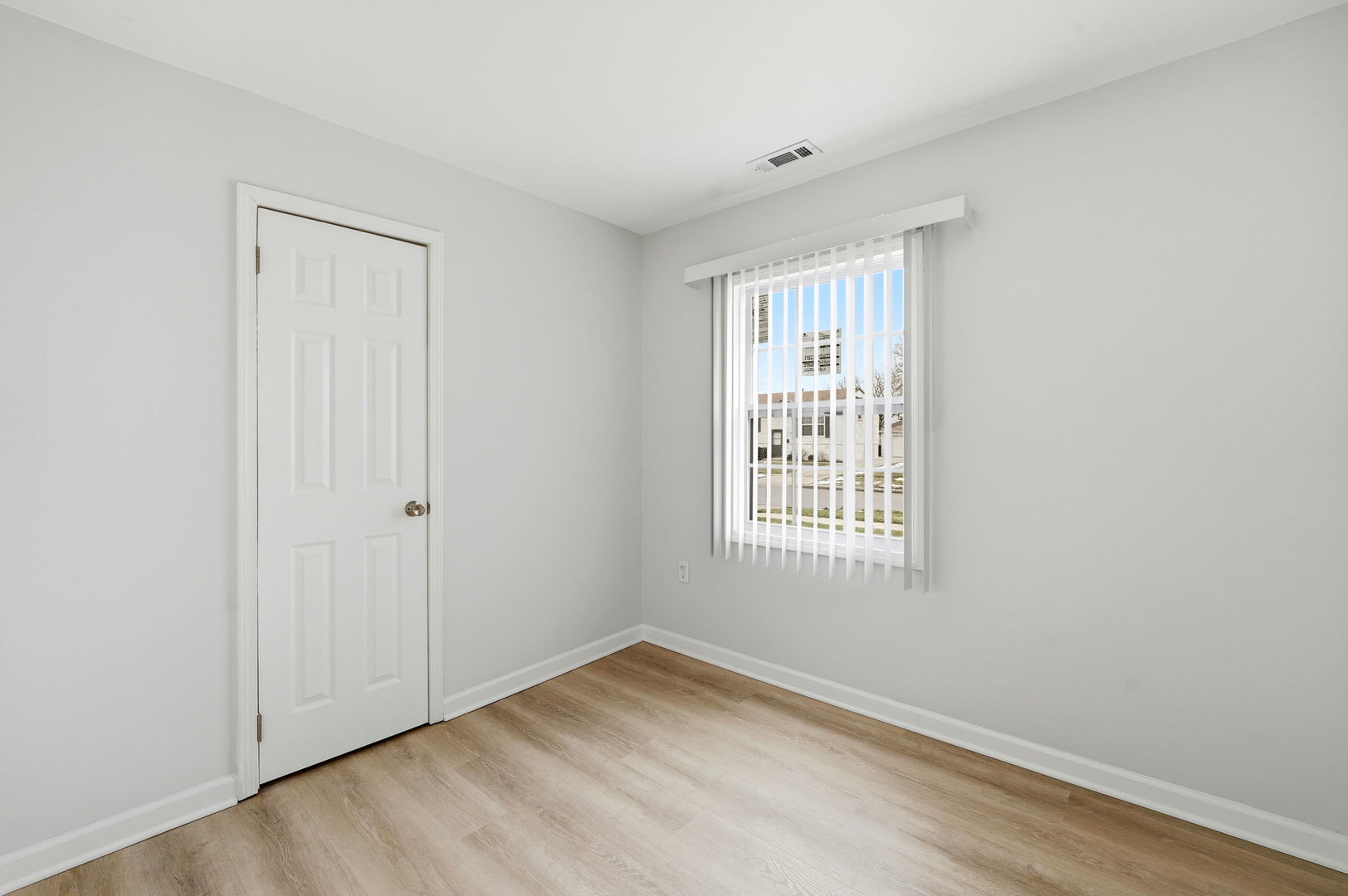 210 Willow Road Streamwood, IL 60107 - Photo 6 of 26 a view of an empty room with wooden floor and a window