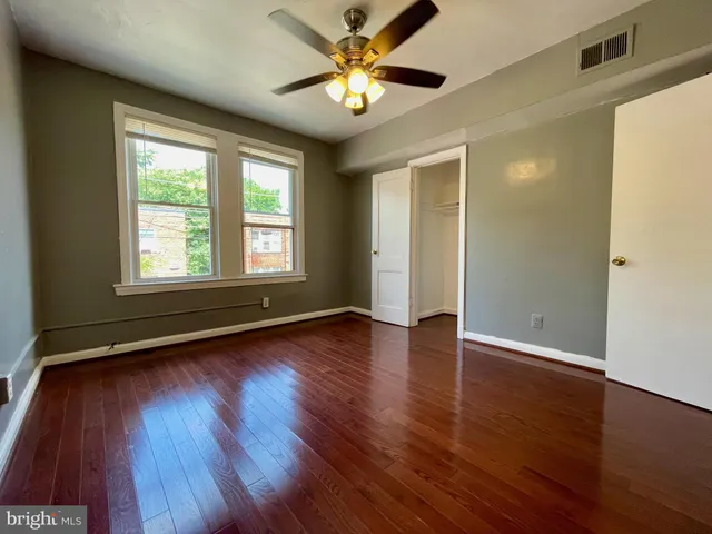 a view of an empty room with window and wooden floor