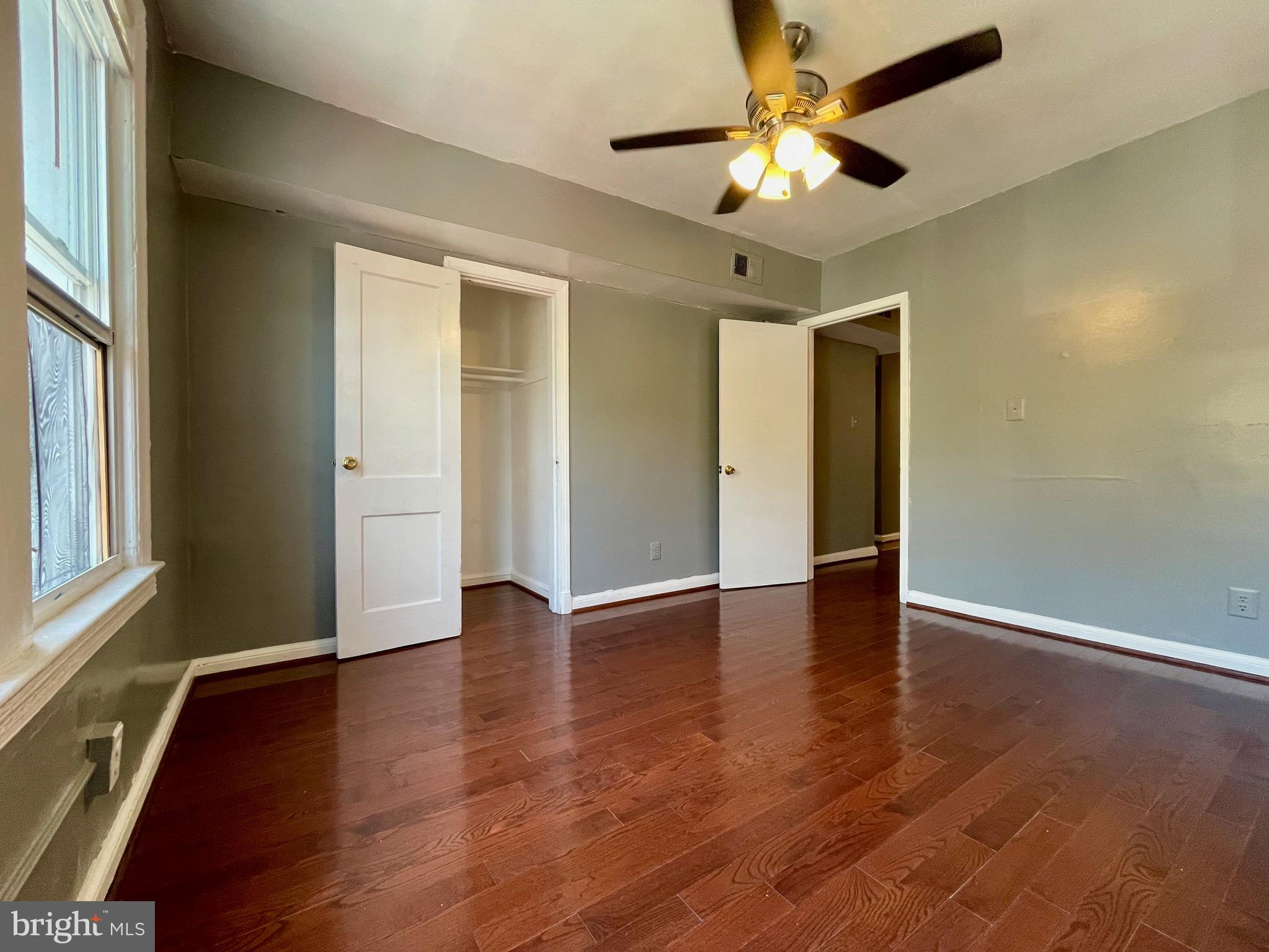 1858 Kendall Street Northeast, Unit 2 Washington, DC 20002 - Photo 13 of 38 an empty room with wooden floor chandelier fan and windows