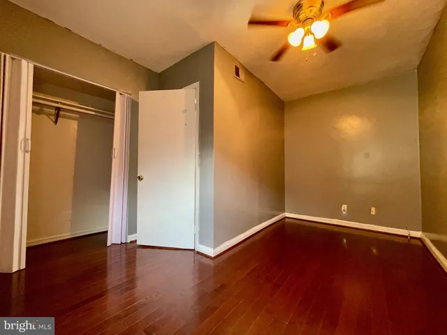 an empty room with wooden floor and a ceiling fan