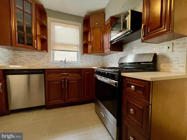 a kitchen with stainless steel appliances granite countertop wooden cabinets and a stove top oven