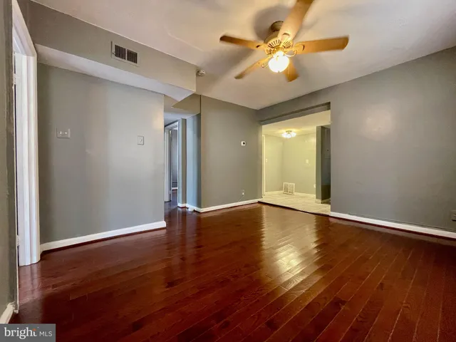 a view of an empty room with window and wooden floor