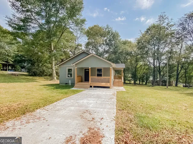 a front view of house with yard and trees in the background