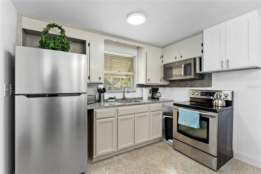 13313 2nd Street East Madeira Beach, FL 33708 - Photo 16 of 36 a kitchen with stainless steel appliances granite countertop a refrigerator sink stove microwave and cabinets