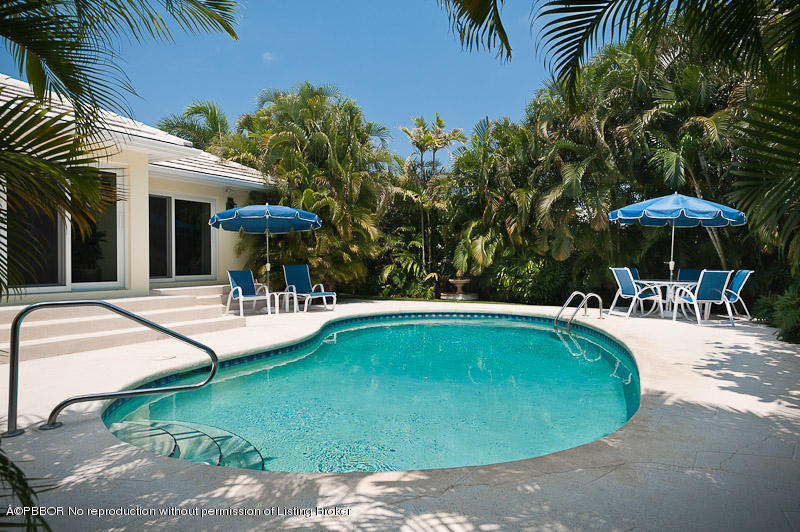 304 Plantation Road Palm Beach, FL 33480 - Photo 2 of 10 a view of a swimming pool with a table and chairs under an umbrella