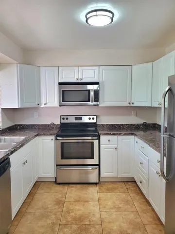 a kitchen with granite countertop a stove top oven and cabinets
