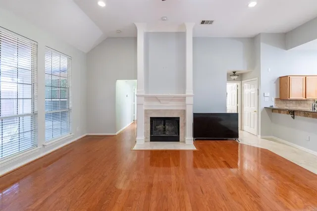 a view of a room with wooden floor fire place and windows