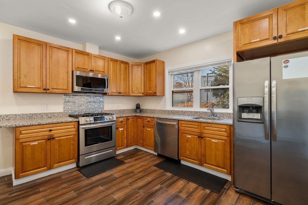 19 Carmen Street, Unit 2 Boston, MA 02121 - Photo 4 of 18 a kitchen with stainless steel appliances granite countertop a refrigerator stove top oven a sink and dishwasher with wooden floor