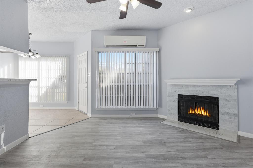 a view of an empty room with wooden floor fireplace and a window