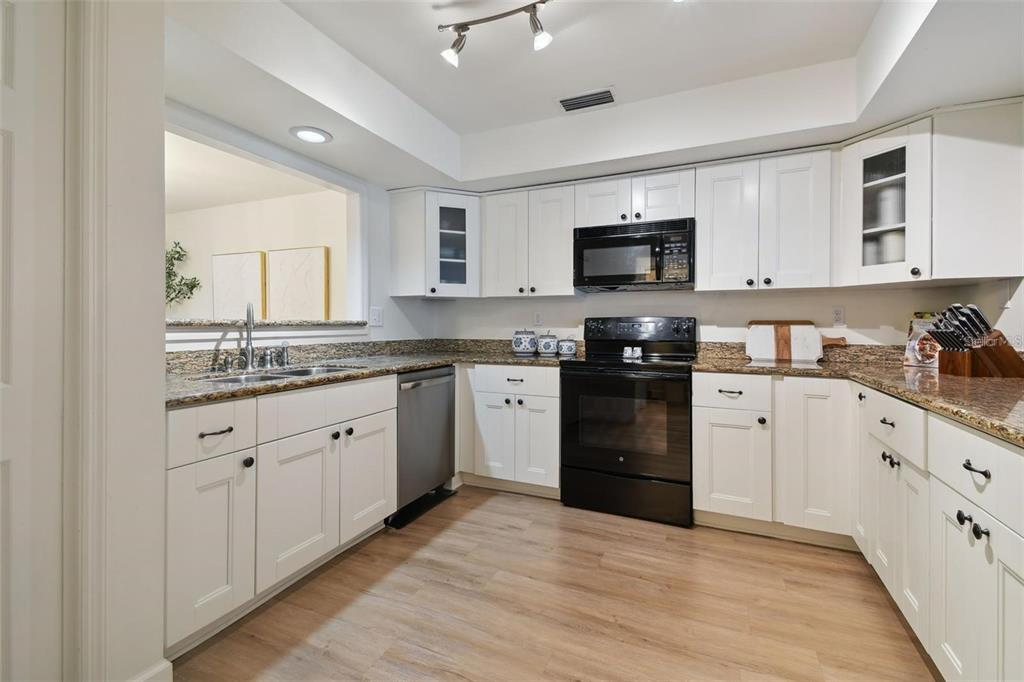 4835 West Flamingo Road Tampa, FL 33611 - Photo 12 of 51 a kitchen with granite countertop white cabinets and black stainless steel appliances