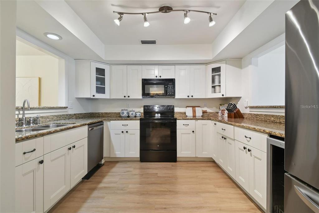 4835 West Flamingo Road Tampa, FL 33611 - Photo 14 of 51 a kitchen with granite countertop white cabinets and black stainless steel appliances