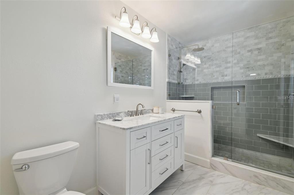 4835 West Flamingo Road Tampa, FL 33611 - Photo 24 of 51 a bathroom with a granite countertop sink a toilet a mirror and shower