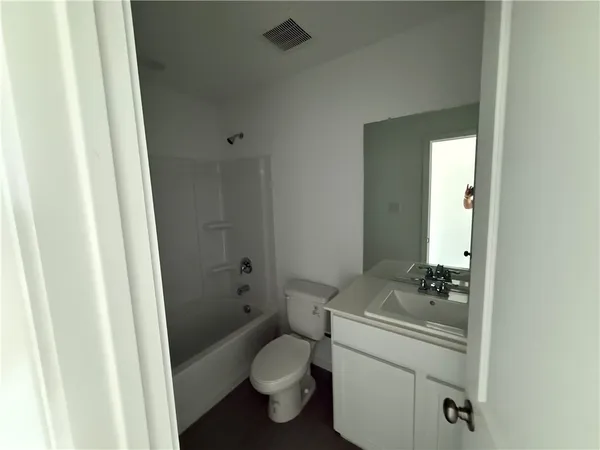 a bathroom with a granite countertop toilet a sink a shower and a mirror
