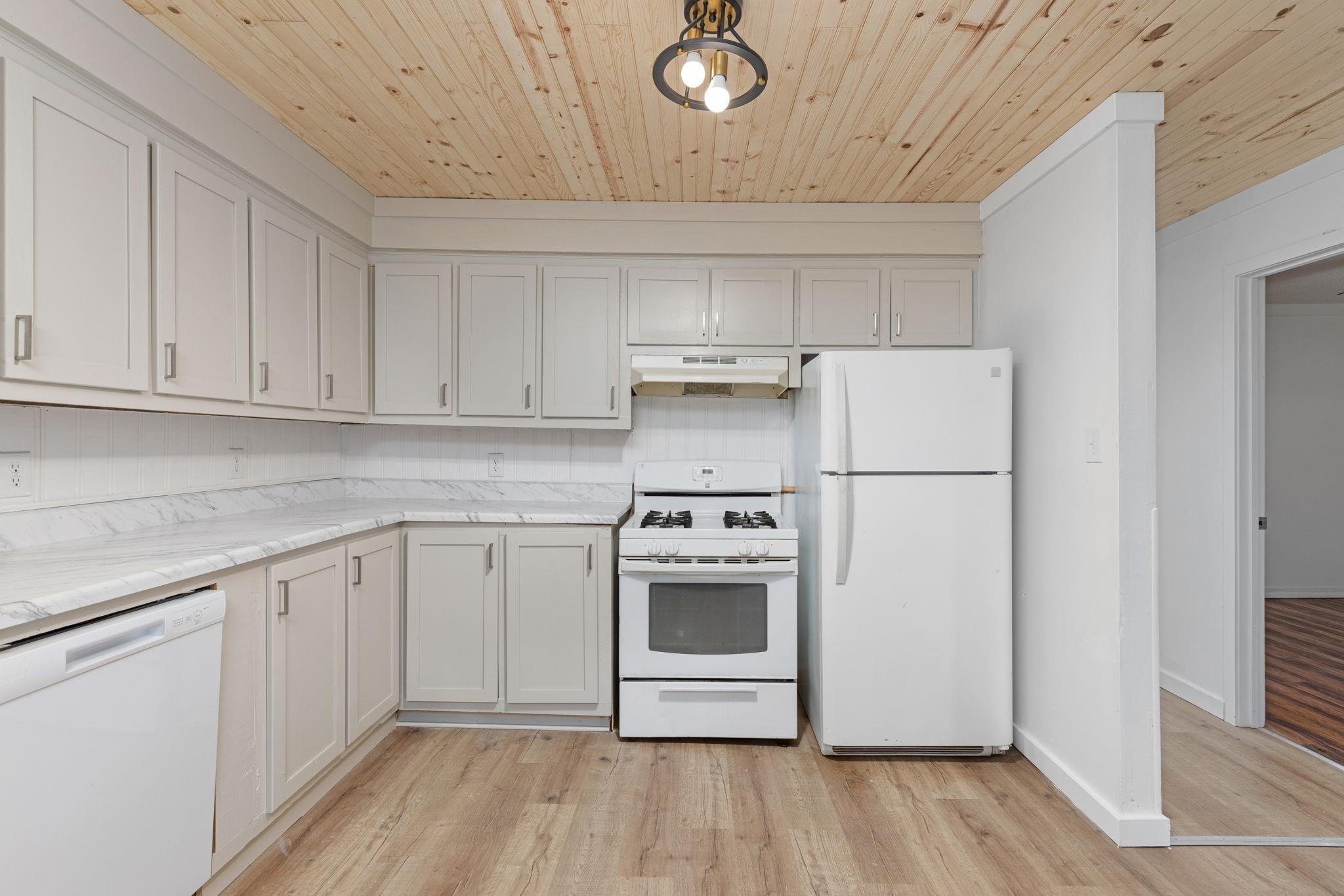 104 Huddleston Drive Ripley, MS 38663 - Photo 8 of 26 Kitchen featuring white appliances, white cabinetry, light hardwood / wood-style floors, light stone counters, and wood ceiling