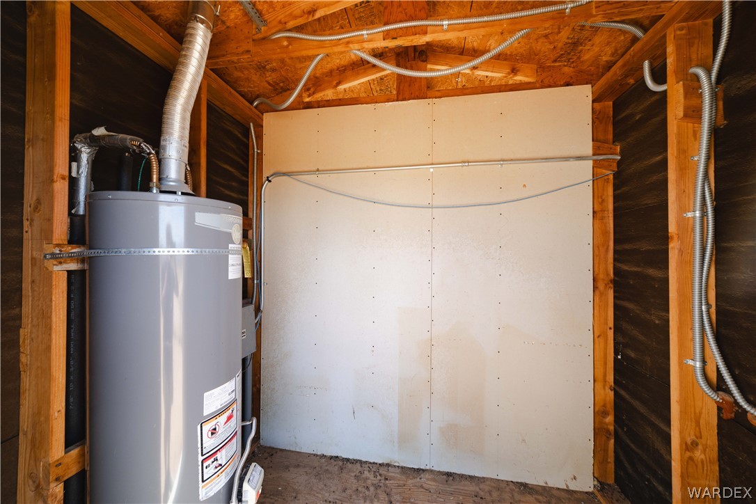 16435 South Wyatt Earp Road Yucca, AZ 86438 - Photo 25 of 57 Utility space featuring a gray water heater, exposed wood framing, and partial drywall