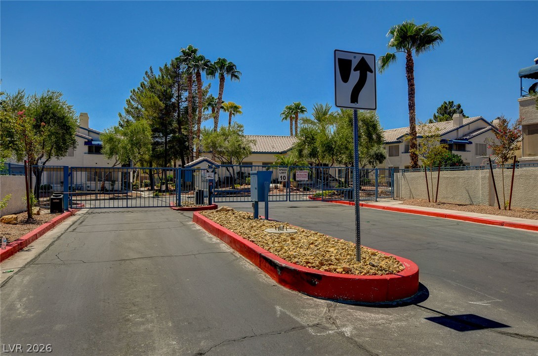 3425 East Russell Road, Unit 223 Las Vegas, NV 89120 - Photo 45 of 47 Secure community entrance with an iron gate, lush trees, and desert-adapted landscaping.
