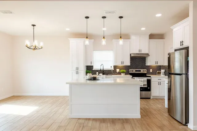 a view of a kitchen with kitchen island stainless steel appliances a stove a center island and a wooden floor