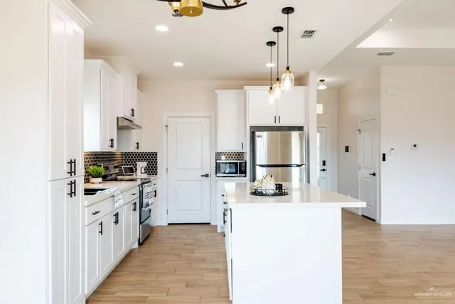 a kitchen with kitchen island granite countertop a sink a counter top space stainless steel appliances and cabinets