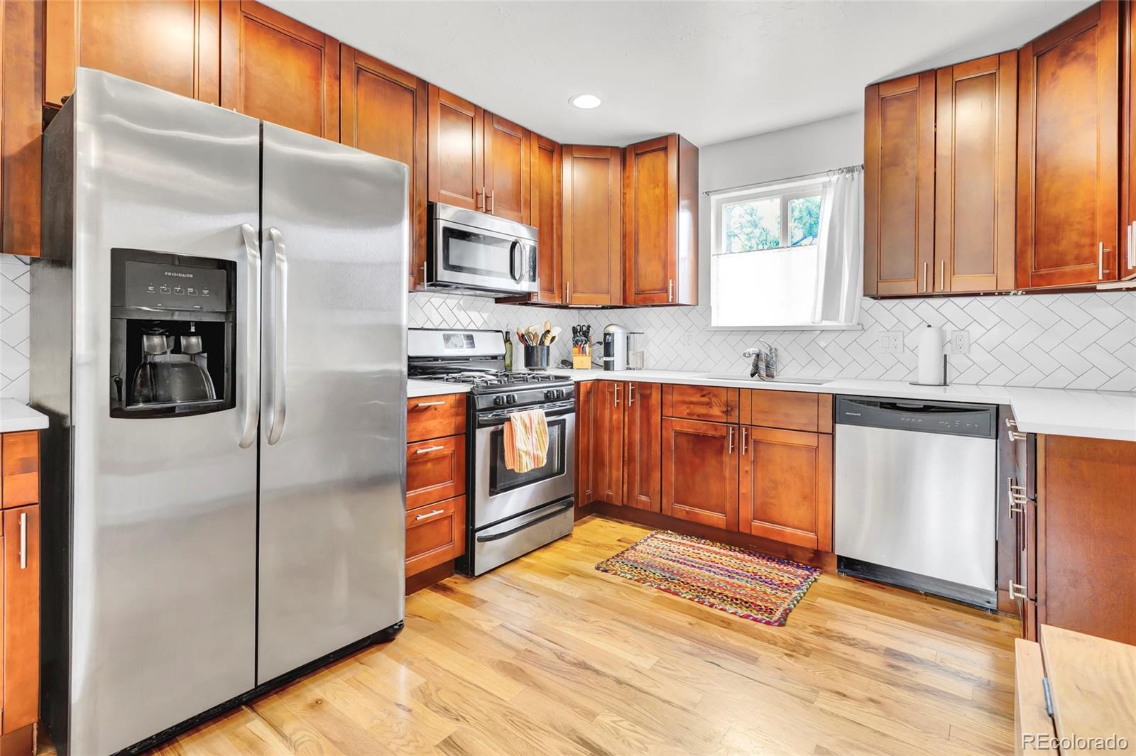 3746 Yates Street Denver, CO 80212 - Photo 5 of 21 a kitchen with stainless steel appliances granite countertop a refrigerator a sink and white cabinets