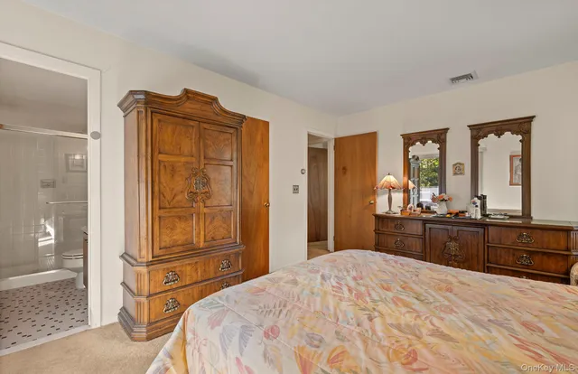 a bedroom with a bed and dresser with mirror