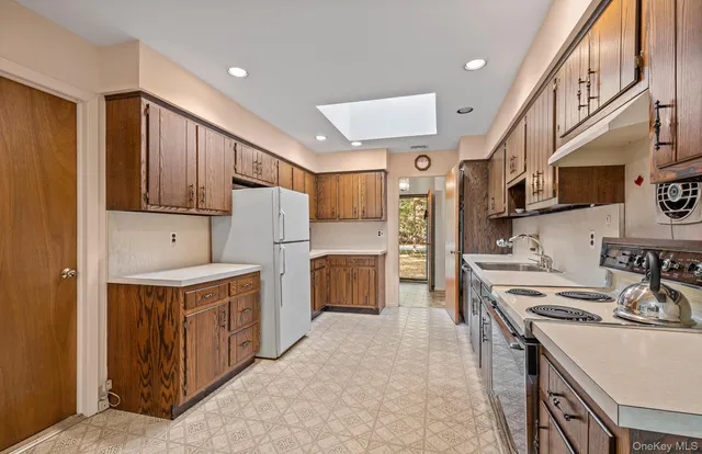 a kitchen with stainless steel appliances granite countertop a stove top oven a refrigerator a sink and dishwasher with wooden floor