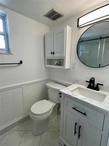 a bathroom with a toilet a sink and mirror