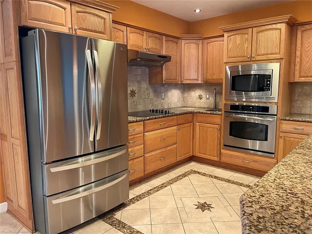 a kitchen with stainless steel appliances granite countertop a refrigerator stove and sink