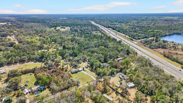 an aerial view of residential houses with outdoor space and trees