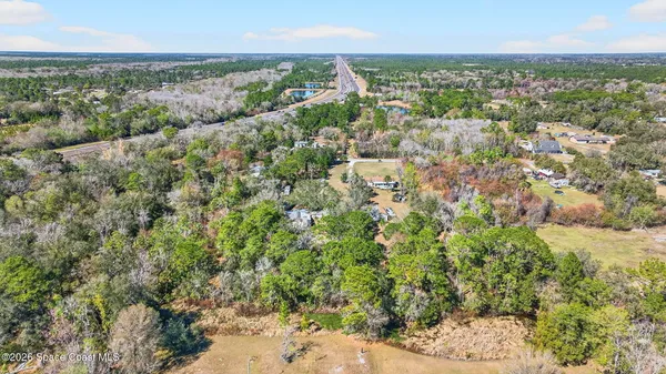 an aerial view of residential houses with outdoor space and trees