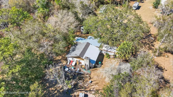an aerial view of a house with outdoor space and trees all around