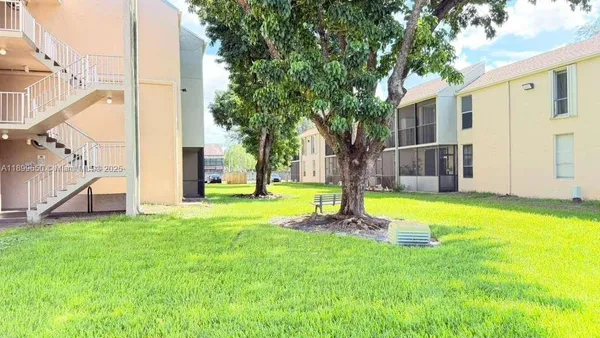 a view of a house with a big yard and large tree