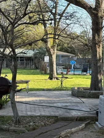 a view of swimming pool with sitting area and large trees