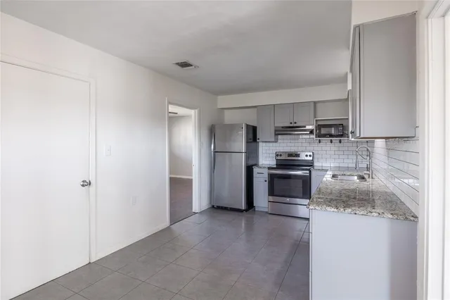 a kitchen with stainless steel appliances granite countertop a refrigerator and a stove