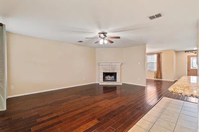 an empty room with wooden floor fireplace and windows