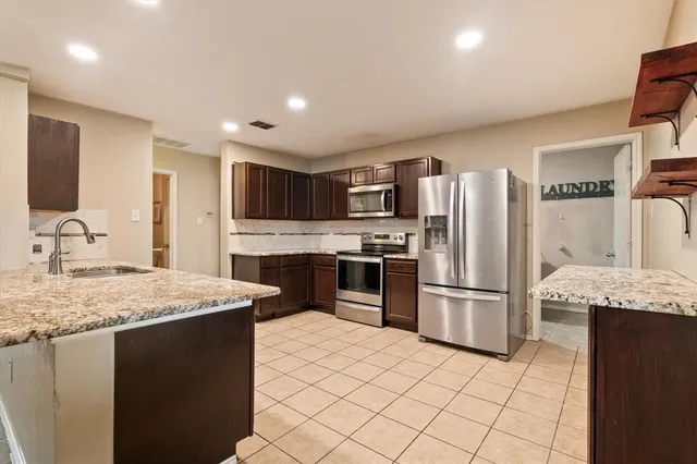 a kitchen with stainless steel appliances granite countertop a refrigerator sink and stove