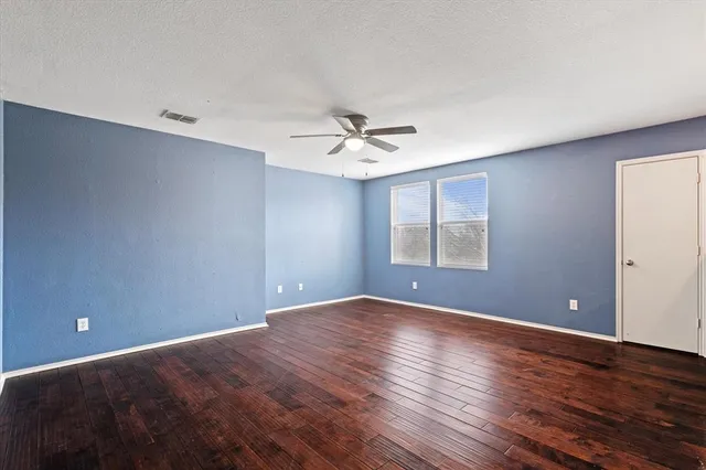 a view of an empty room with window and wooden floor