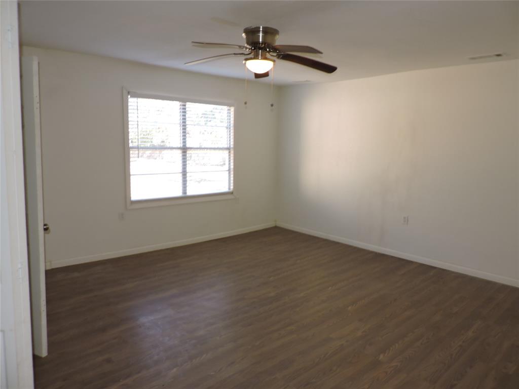 1612 North Anglin Street Cleburne, TX 76031 - Photo 15 of 16 an empty room with wooden floor ceiling fan and windows