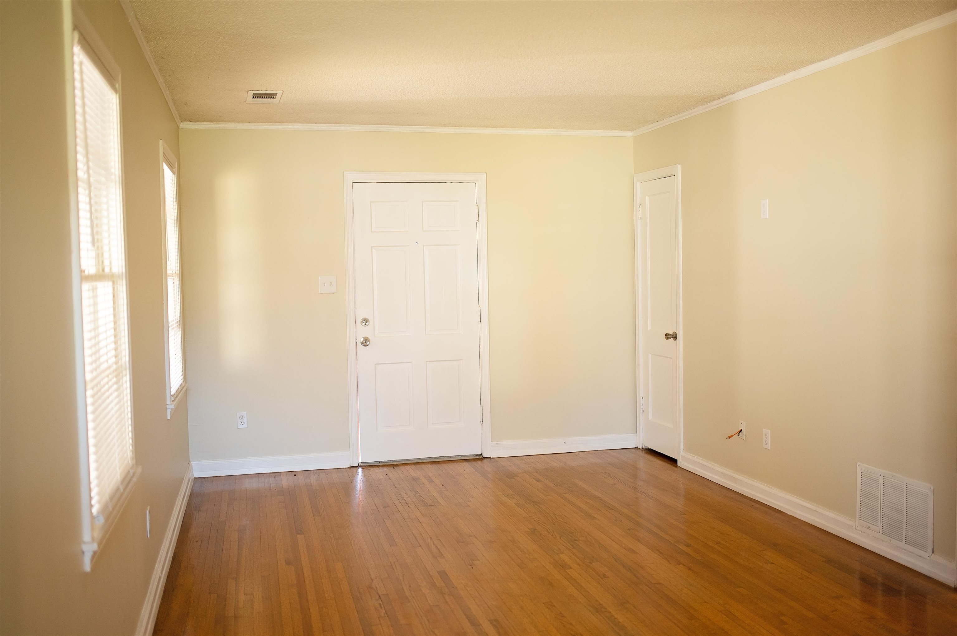 1351 Marcia Road Memphis, TN 38117 - Photo 2 of 10 an empty room with wooden floor and windows with curtains