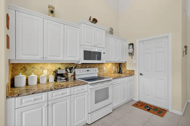 a kitchen with granite countertop white cabinets and white appliances